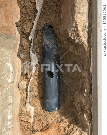 Damaged black pipe leaking water in underground trench 140835561