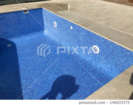 Empty swimming pool with blue mosaic tiles under construction 140835575