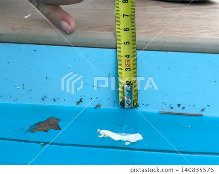 Hand using measuring tape checking pool edge depth Hand using measuring tape checking pool edge depth 140835576