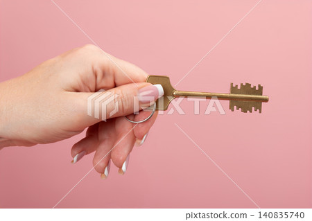 Female hand presenting a golden key on a pink background, symbolizing new home ownership, real estate investment, unlocking opportunities, and financial security Female hand presenting a golden key on a pink background, symbolizing new home ownership, real estate investment, unlocking opportunities, and financial security 140835740