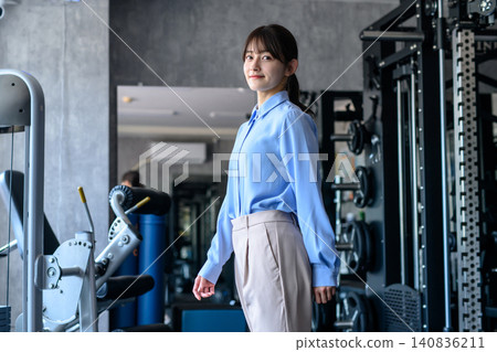 A young woman in office casual attire heads to the gym after work; a fitness enthusiast; dieting; trimming up. A young woman in office casual attire heads to the gym after work; a fitness enthusiast; dieting; trimming up. 140836211