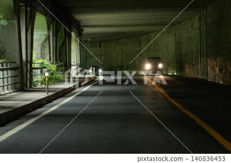 A scene of headlights shining as cars drive through a covered road. A scene of headlights shining as cars drive through a covered road. 140836453