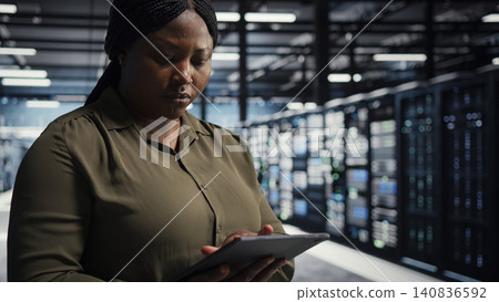 Software developer uses tablet in a server farm to plan disaster recovery and strengthen data protection. Software developer uses tablet in a server farm to plan disaster recovery and strengthen data protection. 140836592