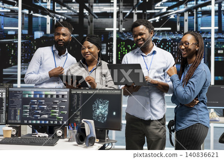 Cheerful high tech server room specialists collaborating, working with deep learning algorithms. 140836621