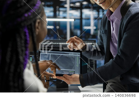 Data center programmers use a digital tablet in a data center to support automation monitoring and reliable server workflows. 140836698