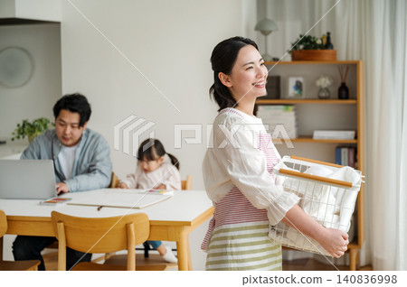 一位年輕的家庭主婦在家洗衣服 一位年輕的家庭主婦在家洗衣服 140836998