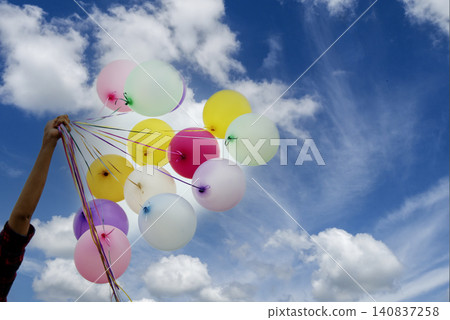 Cheerful beauty woman holding balloons relax sitting under big tree in green park with happiness. Woman Hands holding vibrant air balloons play on birthday party happy time summer on sunshine outdoor Cheerful beauty woman holding balloons relax sitting under big tree in green park with happiness. Woman Hands holding vibrant air balloons play on birthday party happy time summer on sunshine outdoor 140837258