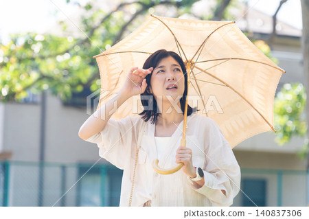 一位身體不適的女士正在使用陽傘。 一位身體不適的女士正在使用陽傘。 140837306