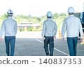 三名身穿工作服的男性工作人員的背影，他們正前往建築工地。 140837353