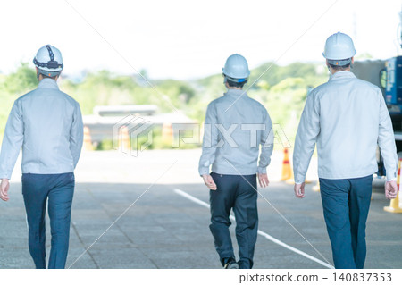 三名身穿工作服的男性工作人員的背影,他們正前往建築工地。 三名身穿工作服的男性工作人員的背影,他們正前往建築工地。 140837353