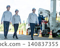三名身穿工作服的男性工作人員在建築工地上行走的全身鏡頭。 140837355