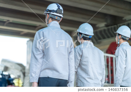 三名身穿工作服的男性工作人員的背影,他們正前往建築工地。 三名身穿工作服的男性工作人員的背影,他們正前往建築工地。 140837356