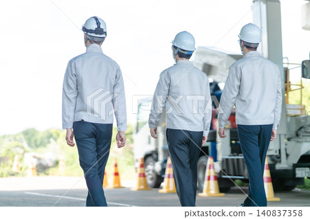 三名身穿工作服的男性工作人員的背影,他們正前往建築工地。 三名身穿工作服的男性工作人員的背影,他們正前往建築工地。 140837358