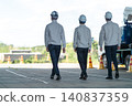 三名身穿工作服的男性工作人員的背影，他們正前往建築工地。 140837359