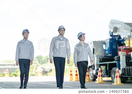 A low-angle front shot of three workers walking in front of a special vehicle. A low-angle front shot of three workers walking in front of a special vehicle. 140837360
