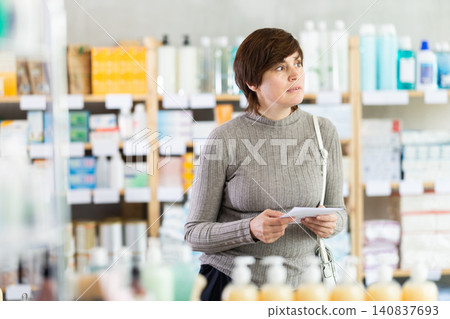 woman with a prescription in her hands choosing some products in supermarket woman with a prescription in her hands choosing some products in supermarket 140837693