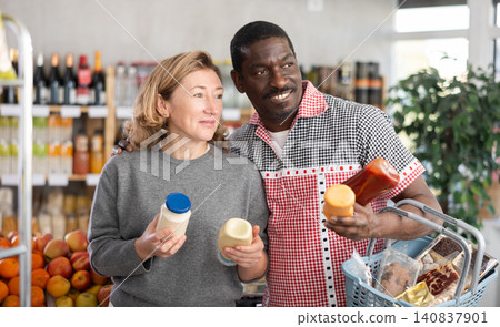 African man with European wife buyer select thoughtfully at bottles of different sauces African man with European wife buyer select thoughtfully at bottles of different sauces 140837901