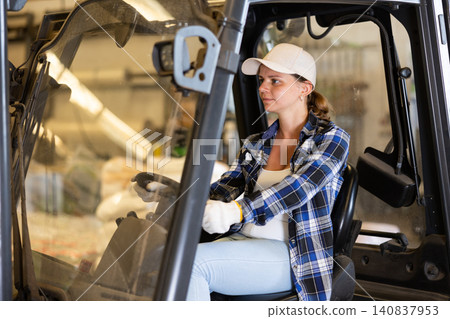 Woman driving fork lift in storehouse Woman driving fork lift in storehouse 140837953