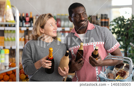 African man with European wife hold bottle and choose alcohol, wine or beer bottle in store African man with European wife hold bottle and choose alcohol, wine or beer bottle in store 140838003