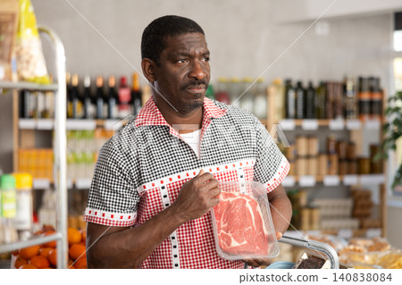 African man choose raw beef entrecote meat for roasting in store African man choose raw beef entrecote meat for roasting in store 140838084