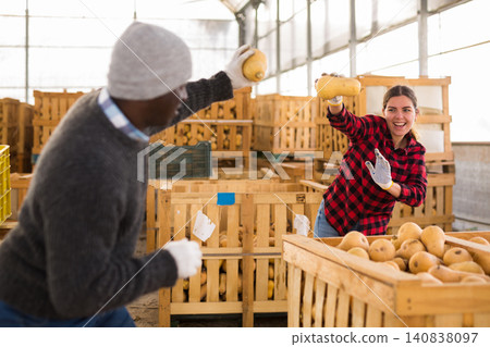 Two warehouse workers having fun and throwing honeynut squashes at each other Two warehouse workers having fun and throwing honeynut squashes at each other 140838097
