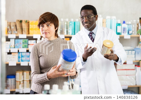 Woman choose buy infant food at pharmacy. African man in background Woman choose buy infant food at pharmacy. African man in background 140838126