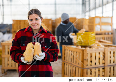 Woman farmer standing with pumpkin Woman farmer standing with pumpkin 140838130