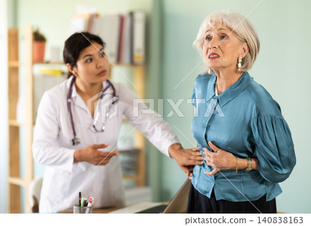 Female doctor examining belly of upset elderly woman patient Female doctor examining belly of upset elderly woman patient 140838163
