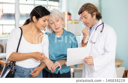 Happy elderly woman with daughter discussing medical tests with doctor Happy elderly woman with daughter discussing medical tests with doctor 140838229