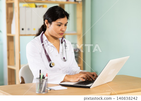 Attentive young female doctor working with laptop Attentive young female doctor working with laptop 140838242