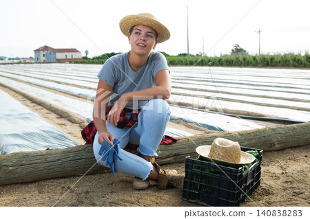 Tired girl worker resting on wooden log after harvesting of peppers Tired girl worker resting on wooden log after harvesting of peppers 140838283