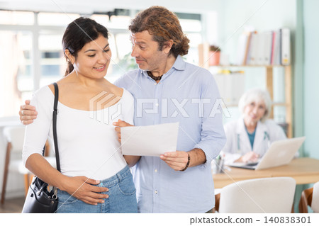 Happy couple holding successful test results in clinical office Happy couple holding successful test results in clinical office 140838301