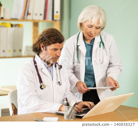 Elderly woman and adult male doctors working on laptop in medical office 140838327