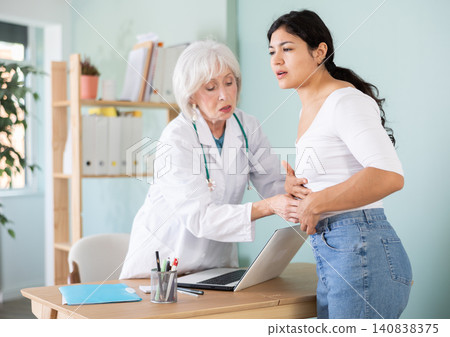 Elderly female doctor examining belly of sad woman patient Elderly female doctor examining belly of sad woman patient 140838375
