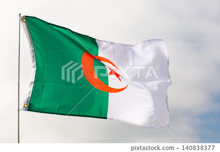 Against background of cloudy sky,white-green flag of Algeria flutters on flagpole Against background of cloudy sky,white-green flag of Algeria flutters on flagpole 140838377