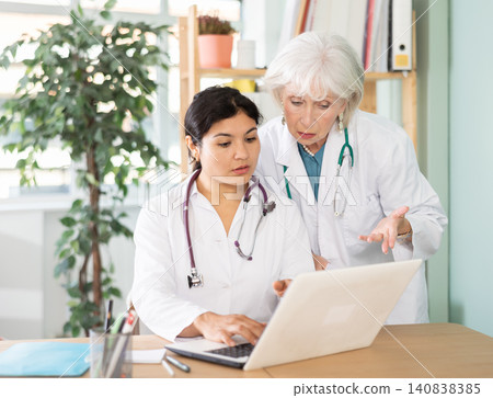 Two female doctors checking medical records on laptop Two female doctors checking medical records on laptop 140838385