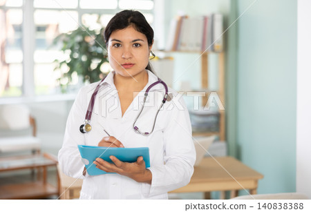 Adult female doctor in medical office holding test results 140838388