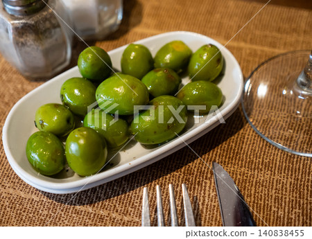 There is full bowl with bright green pickled olives with stone on table 140838455