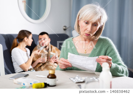 Senior woman reading instruction for medicine to help her sick son at home Senior woman reading instruction for medicine to help her sick son at home 140838462