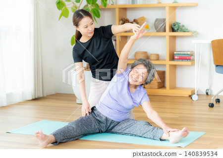 A female trainer assisting seniors with exercise. 140839534