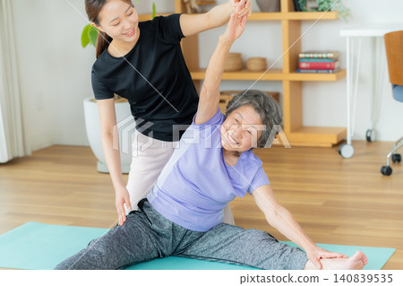 一位女教練正在幫助老年人運動。 140839535