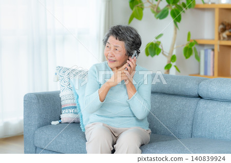 Senior woman making a phone call in the living room Senior woman making a phone call in the living room 140839924