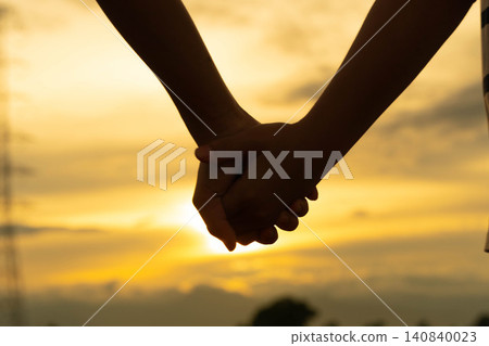 Silhouette of two children holding hands together in love and friendship during golden hour. Silhouette of two children holding hands together in love and friendship during golden hour. 140840023