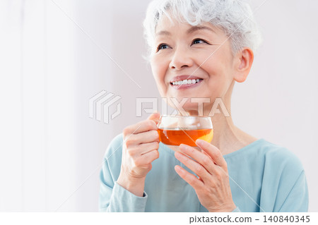 一位老婦人正在喝熱飲 140840345