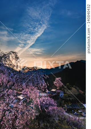 The Shichiro cherry blossoms are in full bloom against a backdrop of nostalgic country houses and distant mountain ranges. 140840432