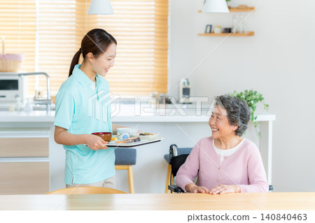 A caregiver assisting a senior woman with a meal. A caregiver assisting a senior woman with a meal. 140840463