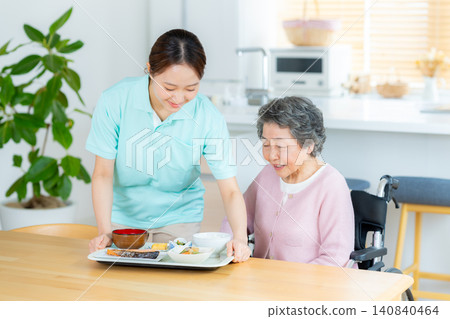 一位護理員正在協助一位老年婦女用餐。 一位護理員正在協助一位老年婦女用餐。 140840464