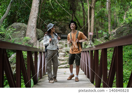 Asian woman tourist talking to boyfriend walking on wooden bridge in forest on mountain hiking trail Asian woman tourist talking to boyfriend walking on wooden bridge in forest on mountain hiking trail 140840828