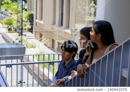 A male and female university student talking on the stairwell landing at the university. 140841078