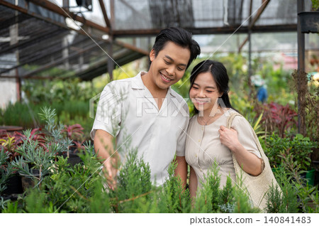 Asian man and woman couple enjoying quality time among plants in a greenhouse nursery garden center. Asian man and woman couple enjoying quality time among plants in a greenhouse nursery garden center. 140841483